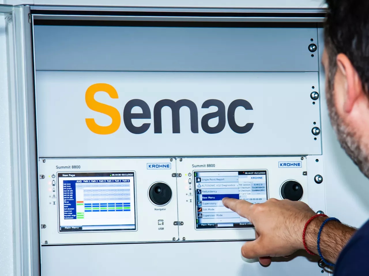 A technician at the touch screen of a flow computer, in a SEMAC metering panel