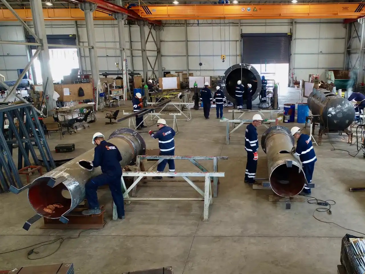 Fabrication crews assembling large pipe sections in the workshop