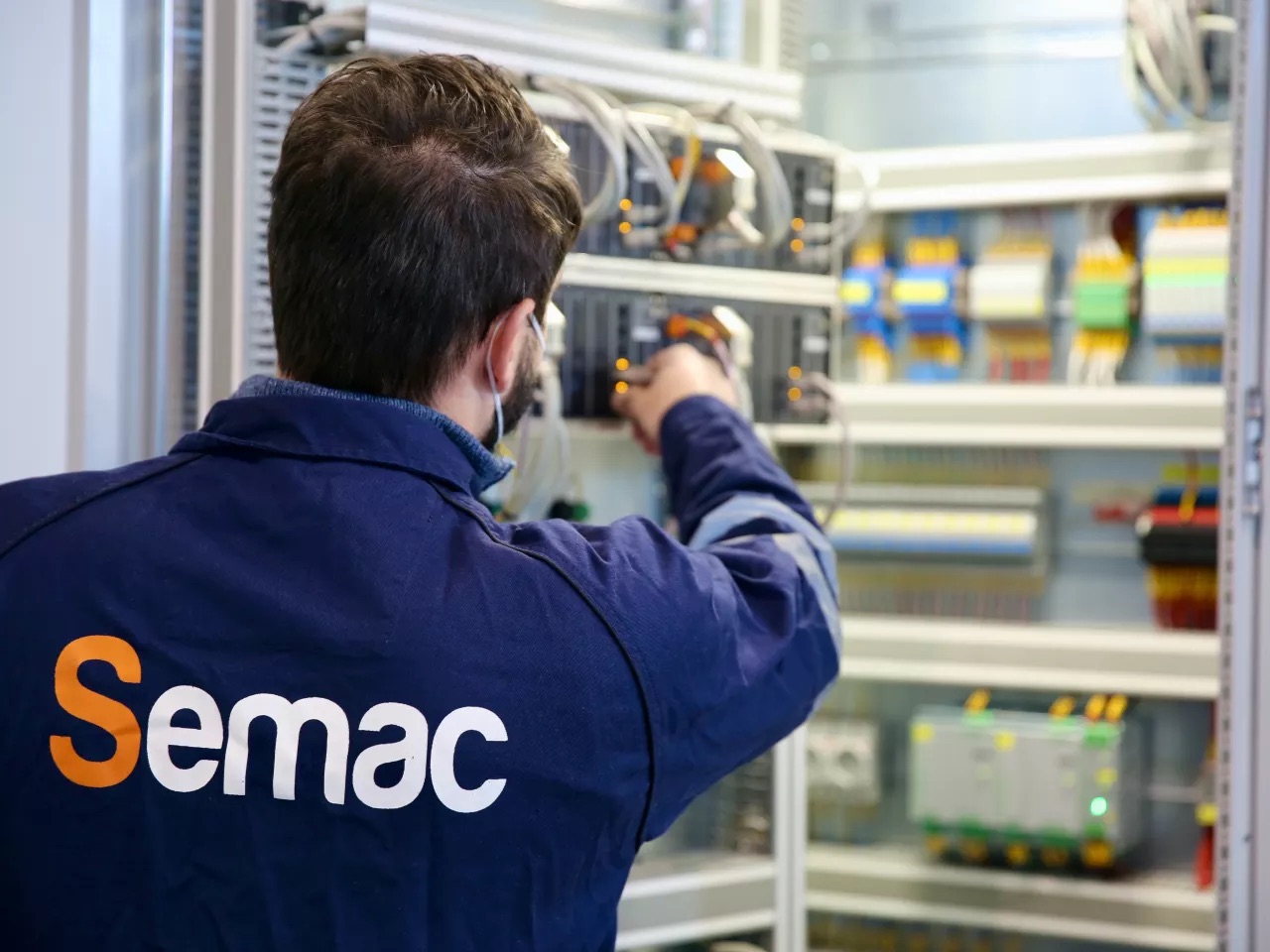 A SEMAC technician wiring equipment inside an automation panel